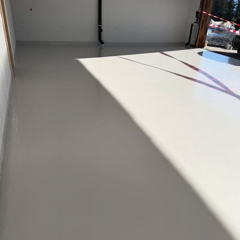 Garage au sol en résine grise, traversé par la lumière