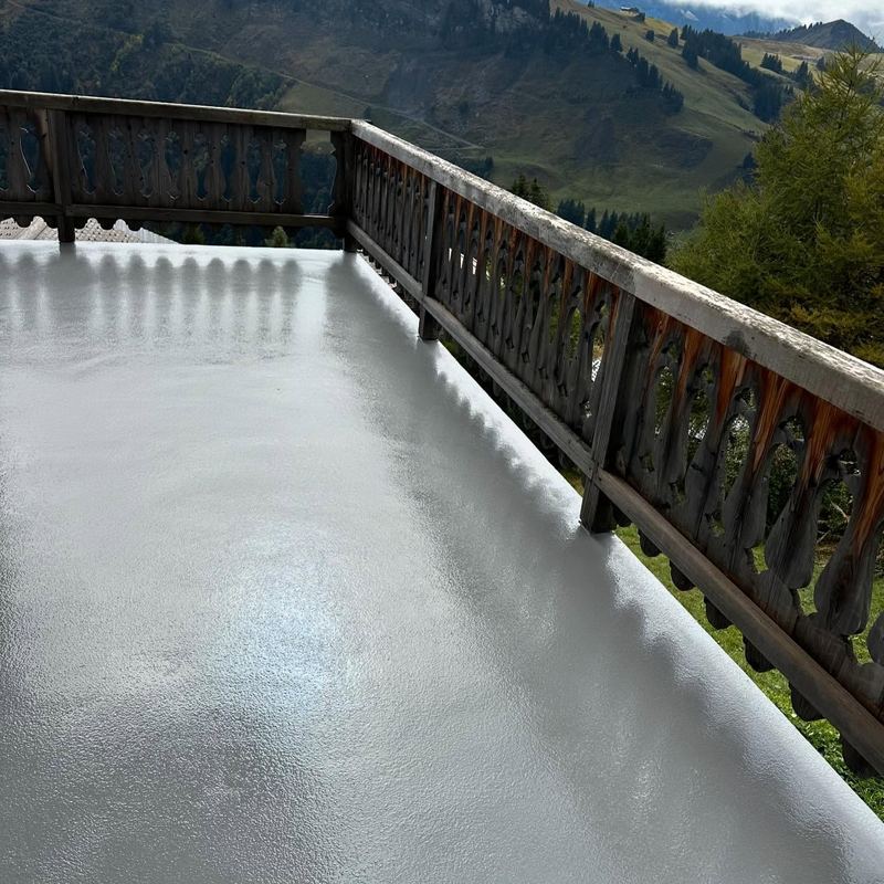 Terrasse de chalet fraîchement résinée, garde-corps en bois et vue sur la montagne